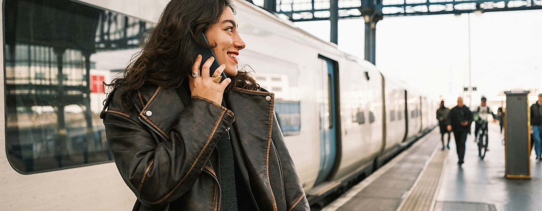 A woman talking on a cell phone at a train station platform.