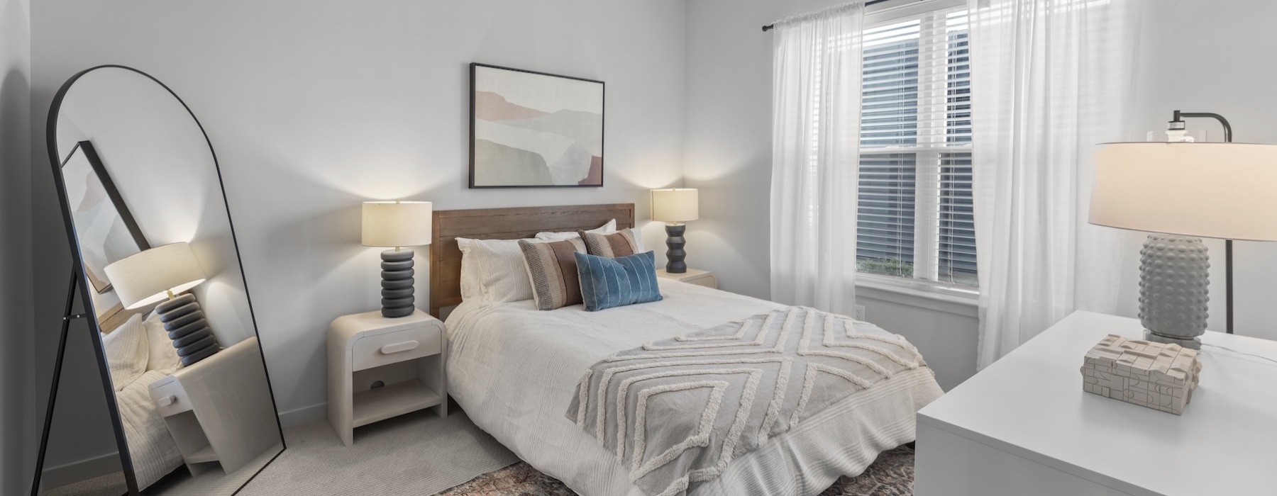 a bedroom with a bed, lamps and a mirror